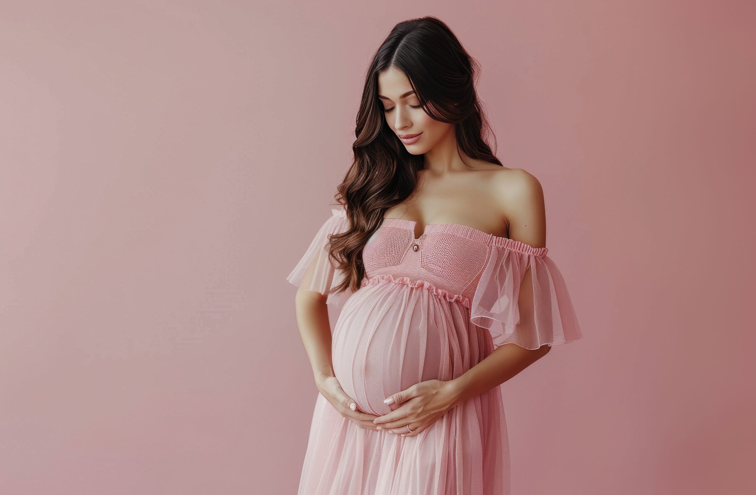 A pregnant woman strikes a pose against a pink background.